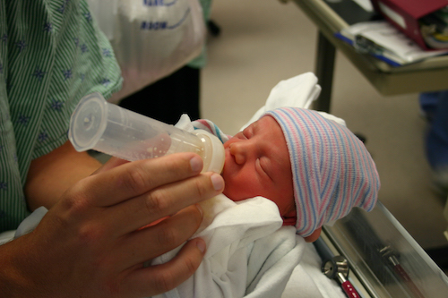 newborn being fed milk from a bottle